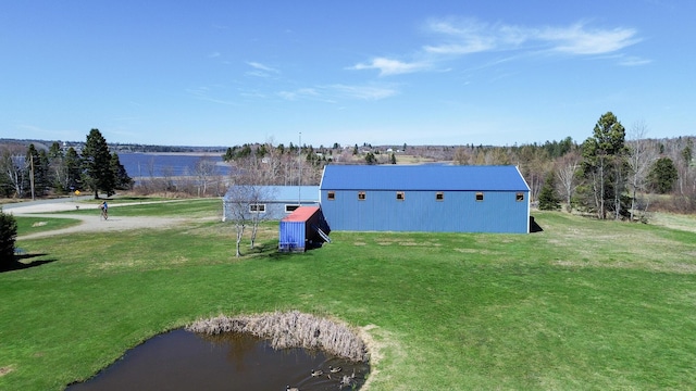 view of green lawn featuring an outbuilding and a water view