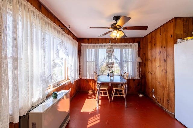 dining area featuring wood walls, plenty of natural light, a ceiling fan, and tile patterned floors