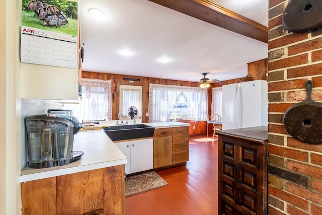 kitchen featuring freestanding refrigerator, a sink, light countertops, wood finished floors, and a peninsula