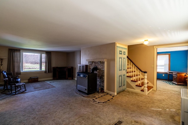 carpeted living area featuring stairs, baseboards, and a wood stove