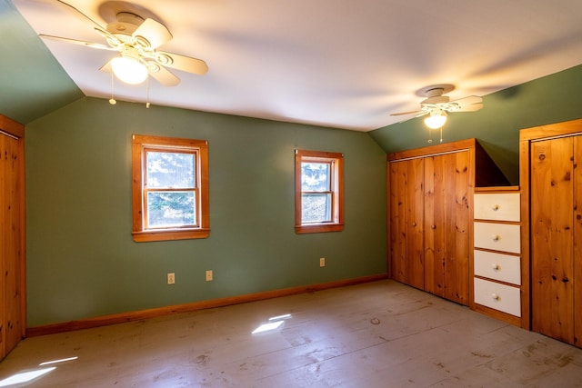 unfurnished bedroom featuring vaulted ceiling, baseboards, ceiling fan, and multiple closets