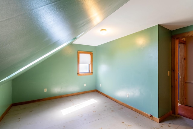 bonus room with lofted ceiling and baseboards