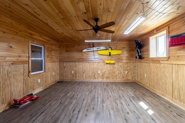 empty room featuring wood ceiling, wood finished floors, baseboards, wood walls, and ceiling fan