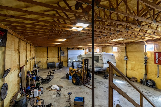 misc room with a garage, concrete floors, and lofted ceiling
