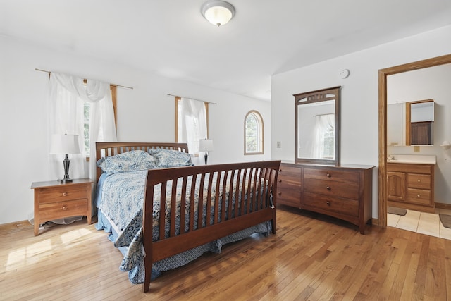 bedroom featuring ensuite bath and light wood-style flooring