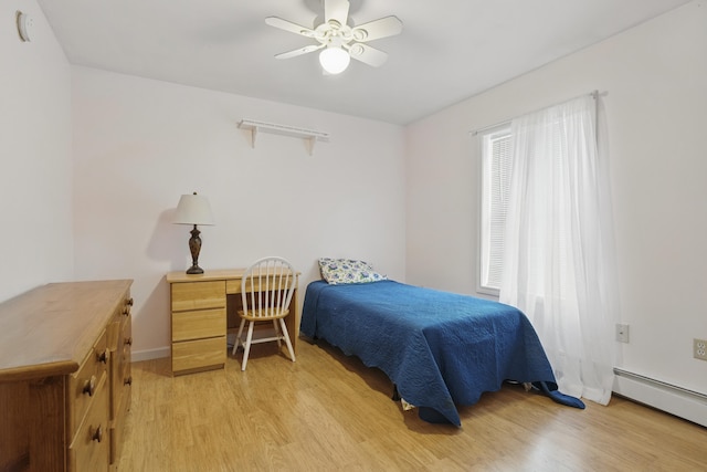 bedroom featuring a baseboard heating unit, light wood-style floors, and ceiling fan