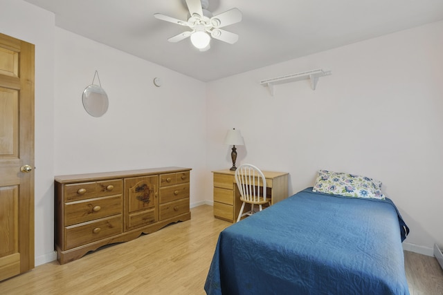 bedroom with light wood-style floors, a ceiling fan, and baseboards