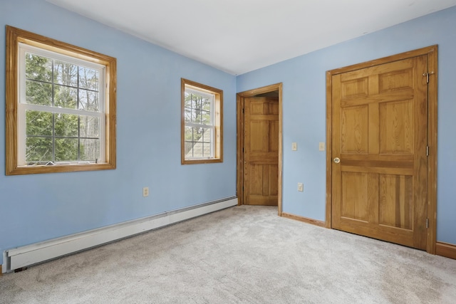 unfurnished bedroom featuring a baseboard heating unit, carpet floors, and baseboards