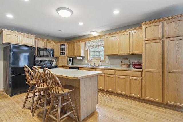 kitchen featuring light countertops, light brown cabinets, and black appliances