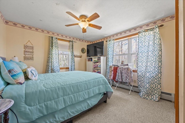 carpeted bedroom with a baseboard heating unit, ceiling fan, multiple windows, and a textured ceiling