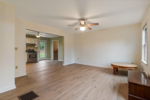 unfurnished room featuring ceiling fan, light wood finished floors, baseboards, and visible vents