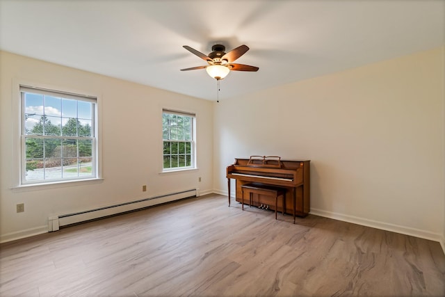 empty room with ceiling fan, wood finished floors, baseboards, and a baseboard heating unit
