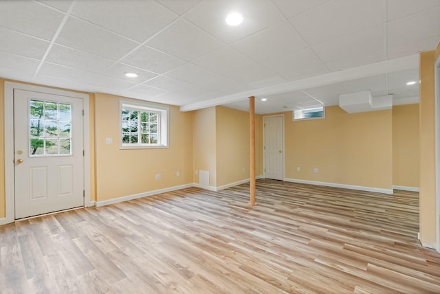 below grade area featuring a paneled ceiling, light wood-style floors, recessed lighting, and baseboards