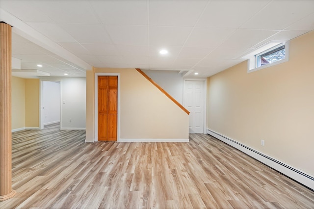 basement with light wood-type flooring, recessed lighting, baseboard heating, a drop ceiling, and baseboards