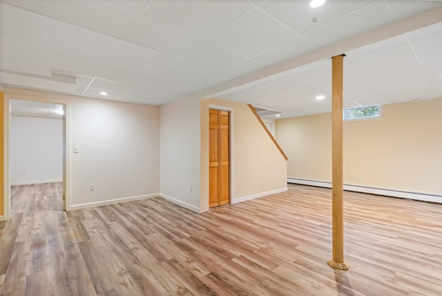 below grade area with wood finished floors, recessed lighting, a baseboard radiator, a drop ceiling, and baseboards