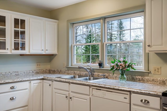 kitchen featuring white cabinetry, white dishwasher, a sink, and glass insert cabinets