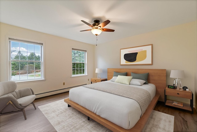 bedroom featuring ceiling fan, wood finished floors, and a baseboard heating unit