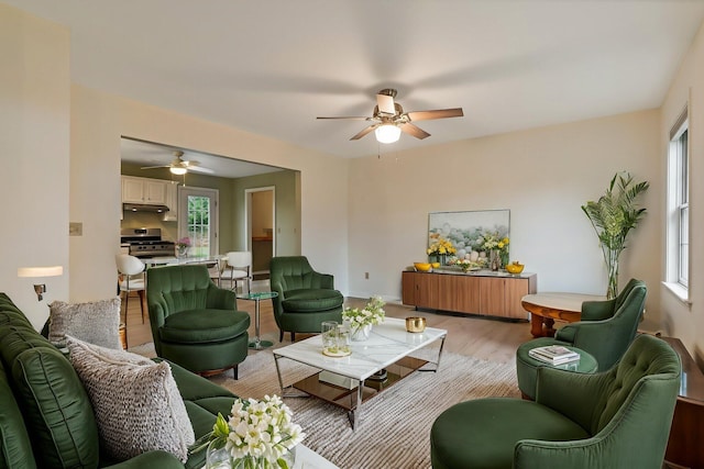living area with light wood finished floors, plenty of natural light, and ceiling fan