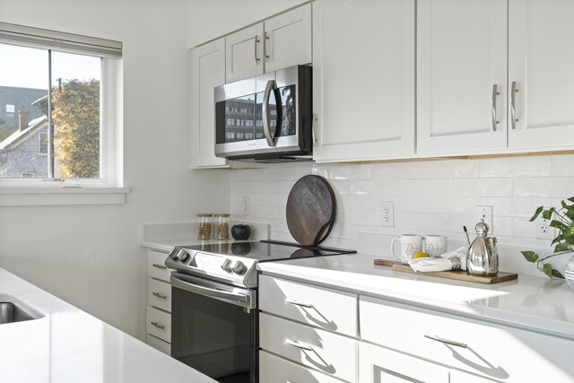 148 Newbury St Unit 2, Portland, ME 04101 - kitchen with light countertops, white cabinetry, appliances with stainless steel finishes, and decorative backsplash