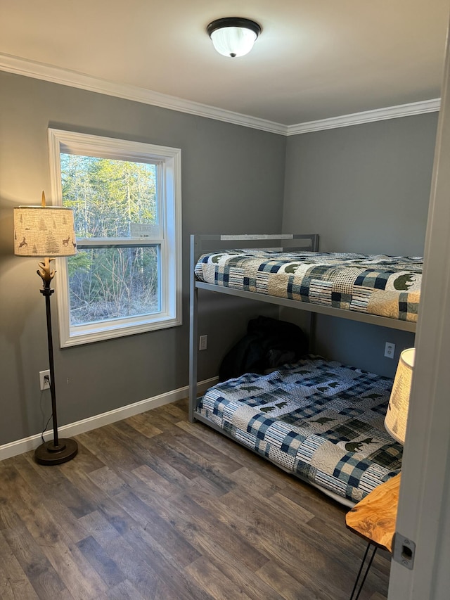 bedroom featuring wood finished floors, crown molding, and baseboards