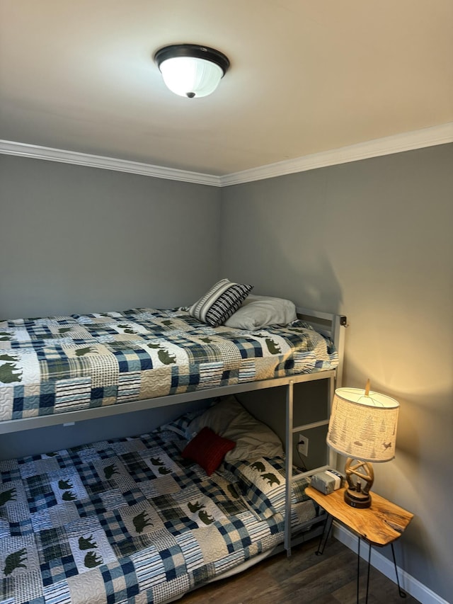 bedroom with baseboards, ornamental molding, and wood finished floors