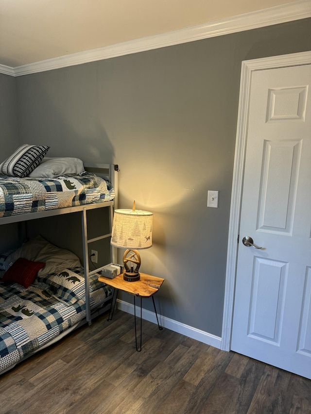 bedroom featuring baseboards, crown molding, and wood finished floors