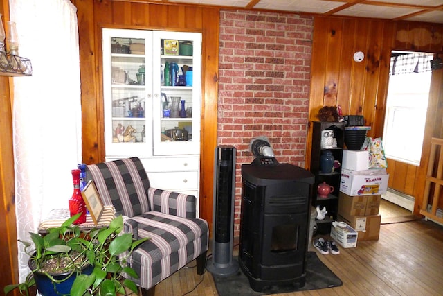 details with baseboard heating, wood walls, a wood stove, and wood finished floors