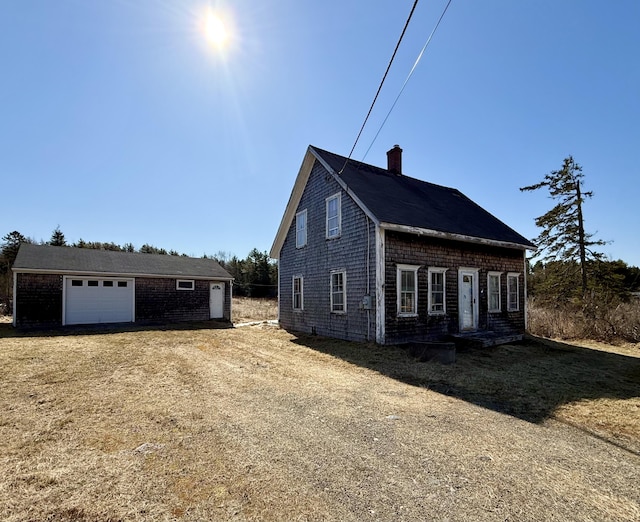 view of side of property featuring a chimney, an outdoor structure, and a garage