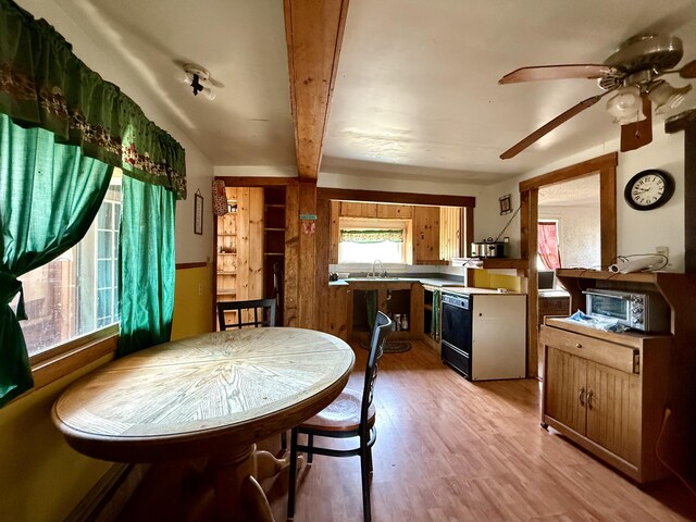 dining area with beamed ceiling, a ceiling fan, a toaster, and light wood-style flooring