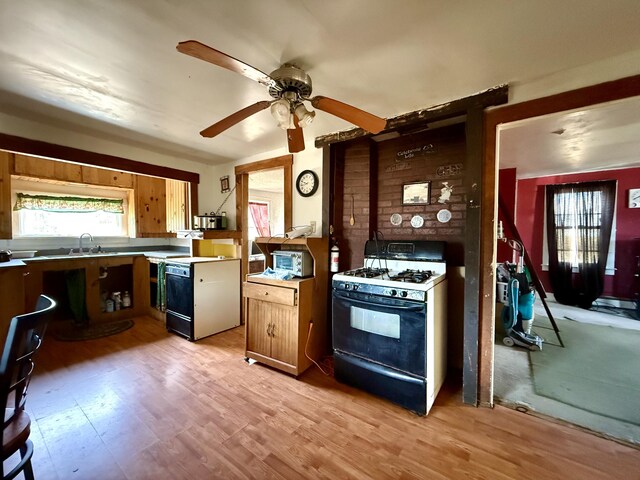 kitchen featuring range with gas stovetop, a sink, light wood-style floors, ceiling fan, and range