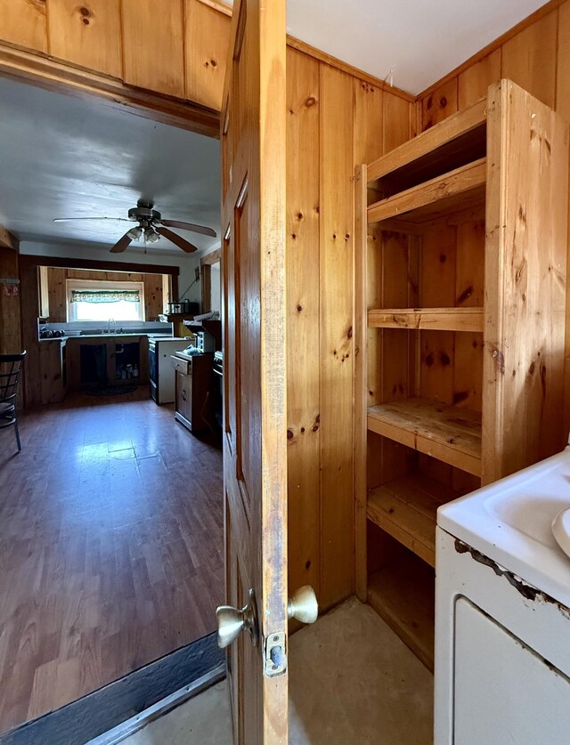 interior space with wooden walls, ceiling fan, and a sink