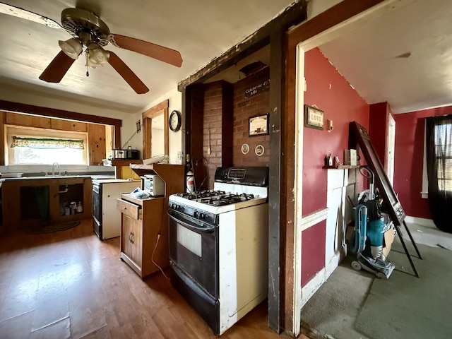 kitchen with gas stove, ceiling fan, and a sink