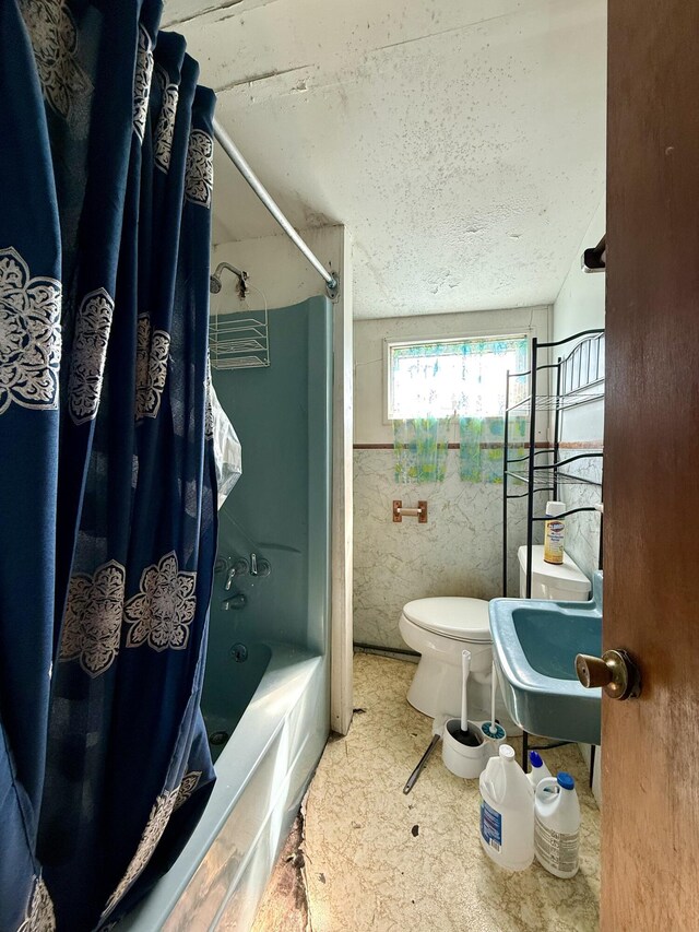 full bathroom featuring shower / tub combo with curtain, a textured ceiling, a sink, and toilet