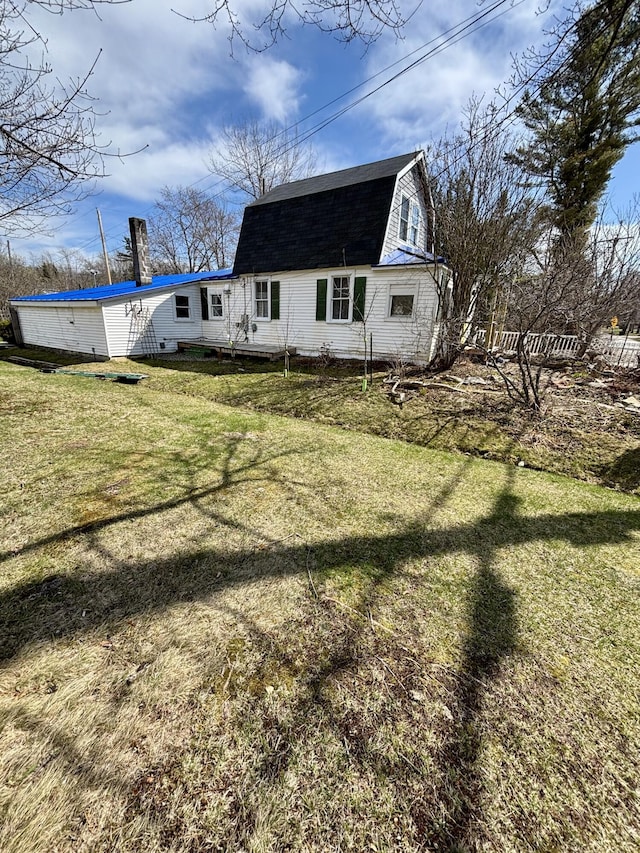 exterior space featuring a gambrel roof, a front lawn, and roof with shingles