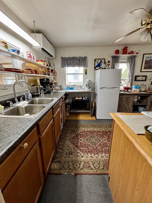 kitchen with a ceiling fan, a wall mounted AC, open shelves, a sink, and freestanding refrigerator