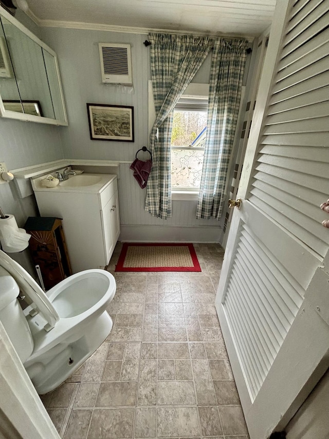 bathroom featuring a sink, ornamental molding, and visible vents