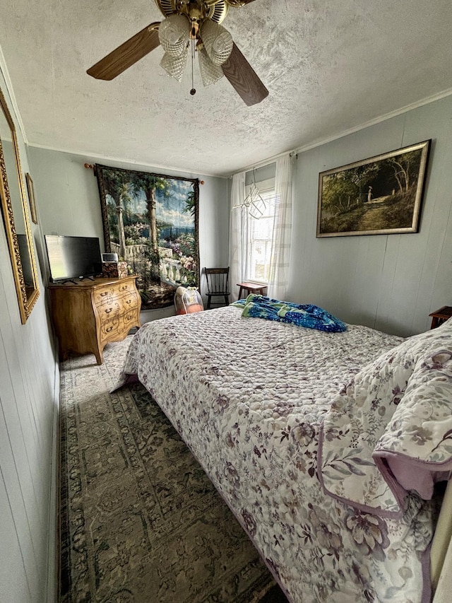 bedroom with a ceiling fan, a textured ceiling, and wooden walls