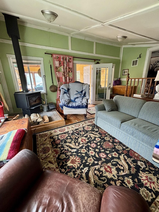 living room with visible vents, a wood stove, and wood finished floors