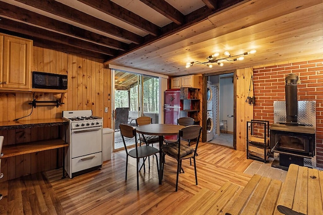 37 Torsey Shores Rd, Readfield, ME 04355 - dining area featuring a wood stove, stacked washing machine and dryer, wood finished floors, and wood walls