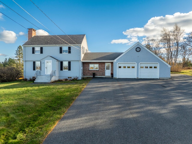 812 County Rd, Lubec, ME 04652 - colonial-style house featuring an attached garage, asphalt driveway, a chimney, a shingled roof, and a front lawn