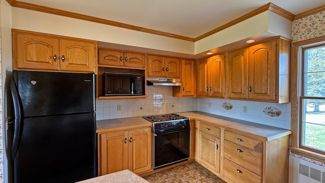 812 County Rd, Lubec, ME 04652 - kitchen featuring black appliances, under cabinet range hood, plenty of natural light, brown cabinetry, and ornamental molding