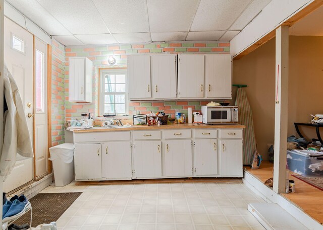 84 Hillside Rd, Westbrook, ME 04092 - kitchen with white cabinetry, light countertops, white microwave, and a paneled ceiling