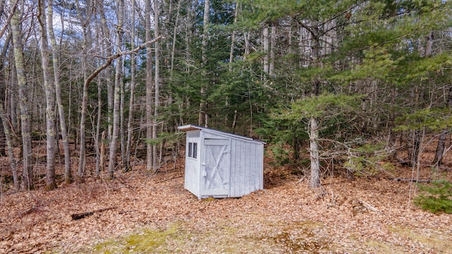 view of yard with a storage shed, a wooded view, and an outbuilding