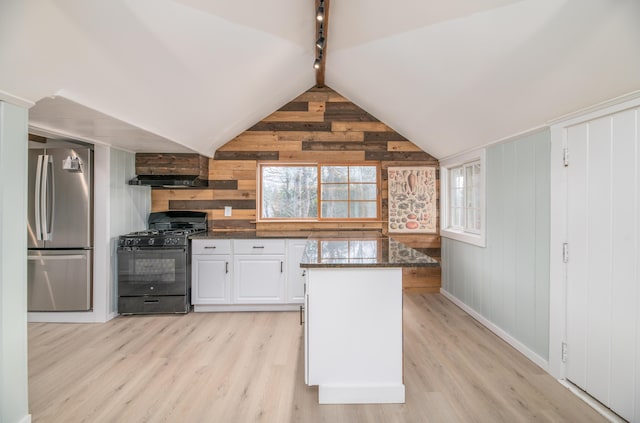 kitchen with dark stone countertops, black gas stove, light wood finished floors, and freestanding refrigerator