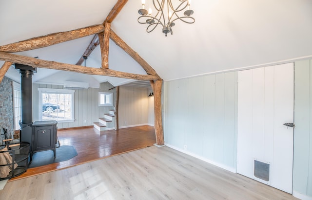 additional living space featuring wood finished floors, stairway, a chandelier, an AC wall unit, and a wood stove