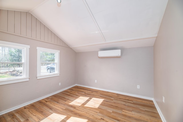 bonus room with lofted ceiling, wood finished floors, an AC wall unit, and baseboards