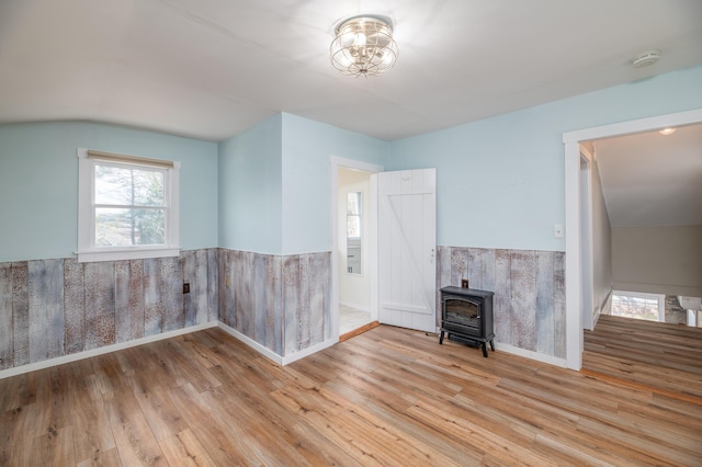 interior space featuring a wood stove, a wainscoted wall, and wood finished floors