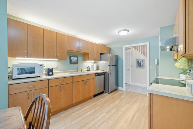 12 Ephraim Tyler Way Unit 12, Kennebunk, ME 04043 - kitchen featuring appliances with stainless steel finishes, a sink, light countertops, range hood, and light wood-style floors