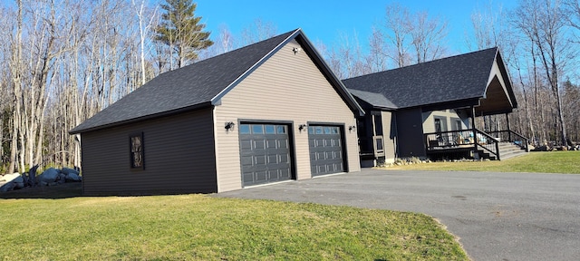 view of side of home with aphalt driveway, covered porch, a yard, and roof with shingles