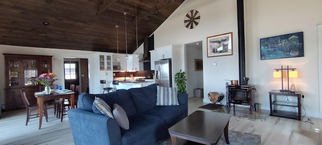 living area featuring high vaulted ceiling, light wood-type flooring, a wood stove, and wood ceiling